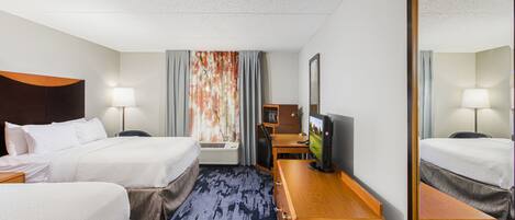 A hotel room with two beds, a desk with a computer, a TV, and a large mirror.