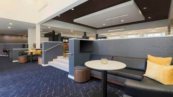 A modern lounge area with a sofa, round table, and a staircase leading to an upper level.