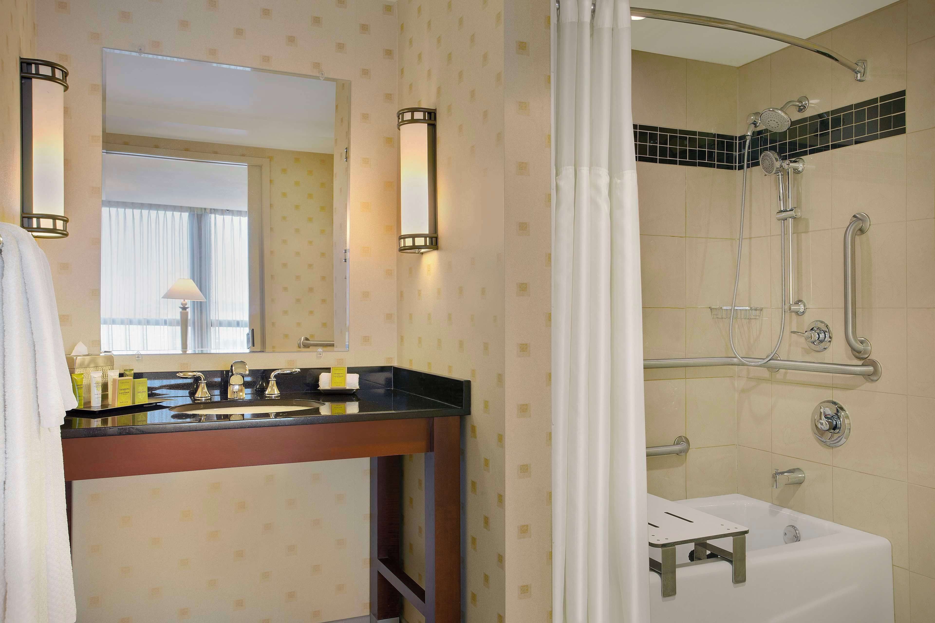 A bathroom with a vanity, sink, mirror, and shower.