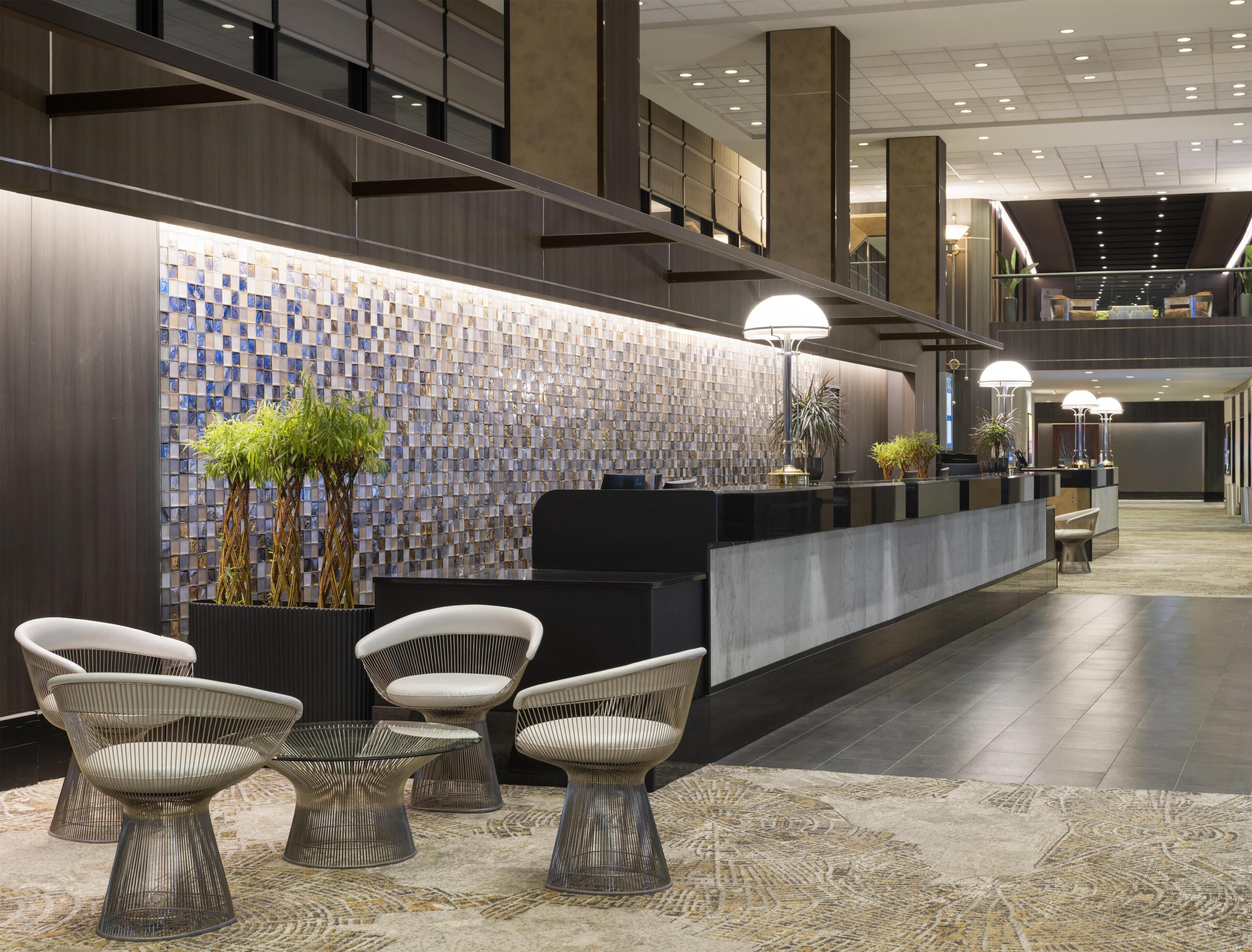 A modern reception area with a check-in counter, seating, and a decorative wall.