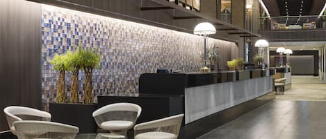 A modern reception area with a check-in counter, seating, and a decorative wall.