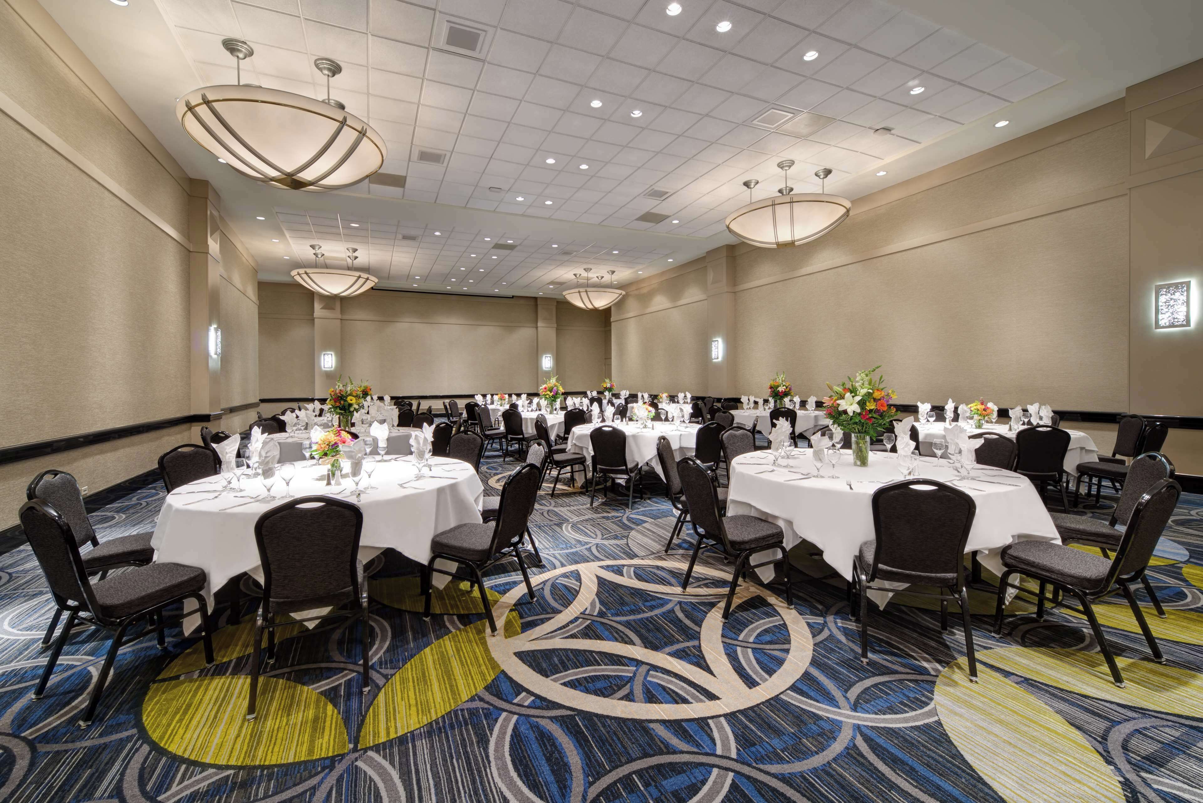 A large conference room with multiple round tables, each set with chairs and centerpieces.