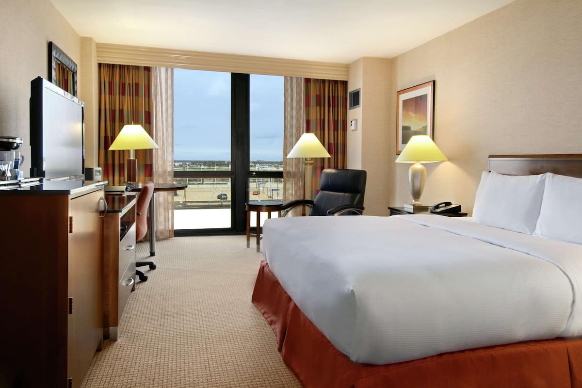 Een hotelkamer met een groot bed, twee bedlampen, een bureau met een computer en een stoel.