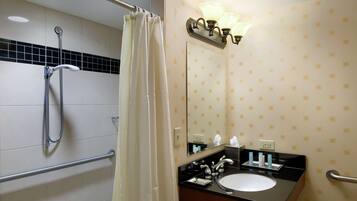 A bathroom with a shower, a sink, a mirror, and a towel rack.