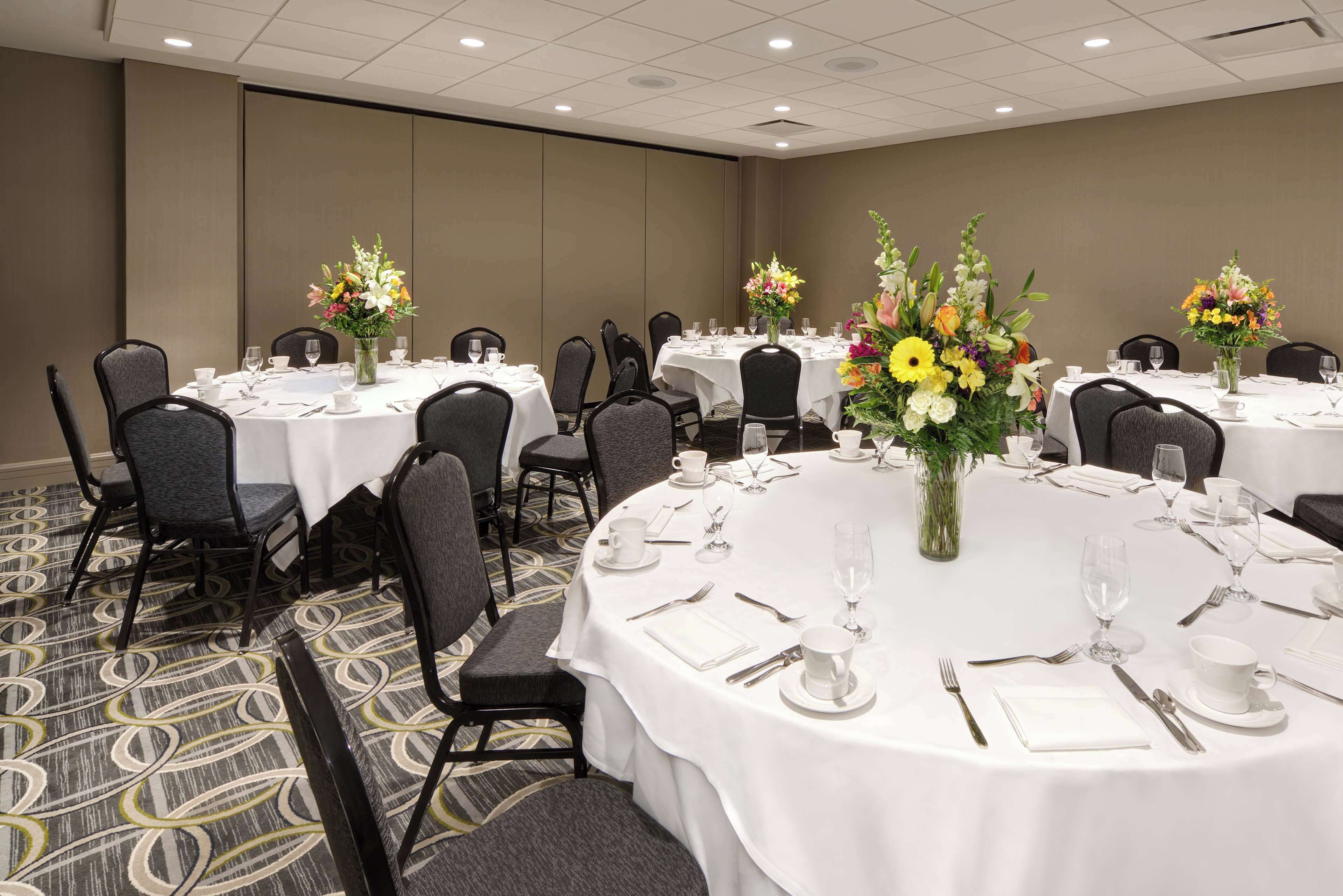 A conference room with round tables, chairs, and floral centerpieces.