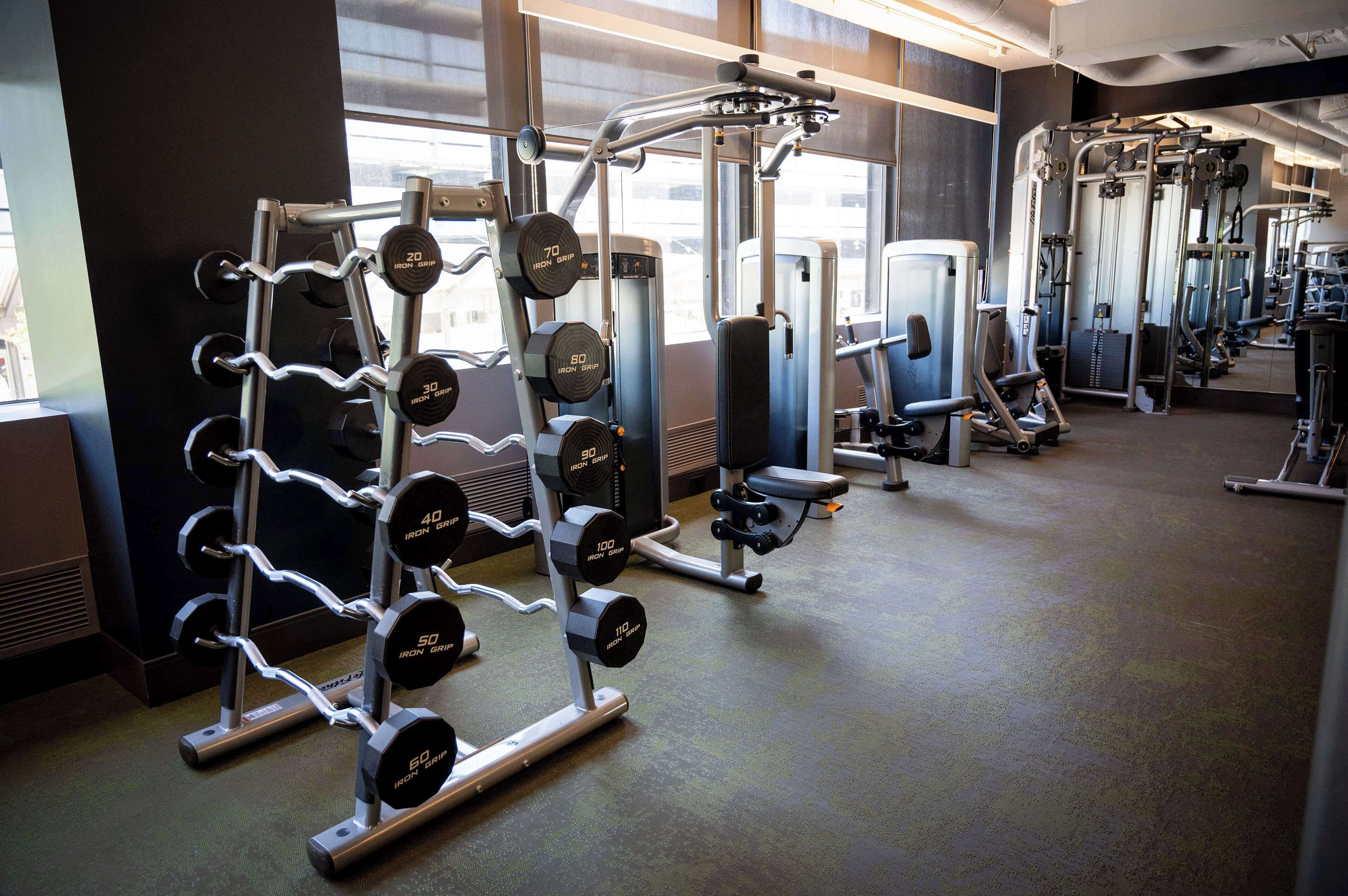 A gym with weightlifting equipment, cardio machines, and mirrors on the walls.