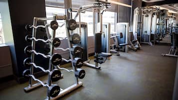 A gym with weightlifting equipment, cardio machines, and mirrors on the walls.