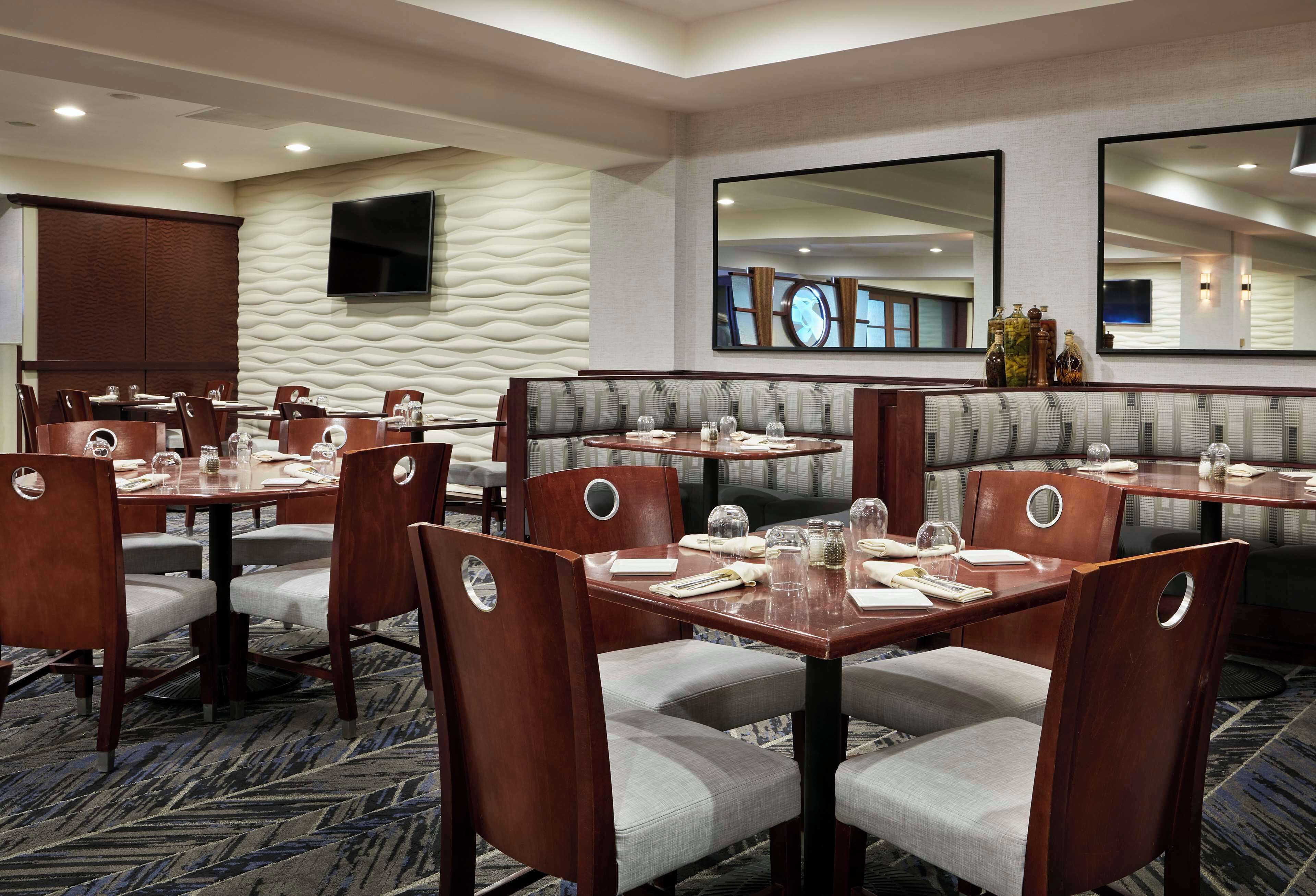 A hotel dining area with multiple tables and booths, equipped with chairs and dining essentials.