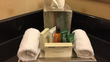 A bathroom counter with a tissue box, a massaging bar, and two towels.