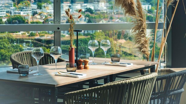 A dining table set with wine glasses, a vase with dried plants, and salt and pepper shakers.