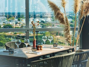 A dining table set with wine glasses, a vase with dried plants, and salt and pepper shakers. - Mercure Paris Orly Rungis Aéroport (Rungis)