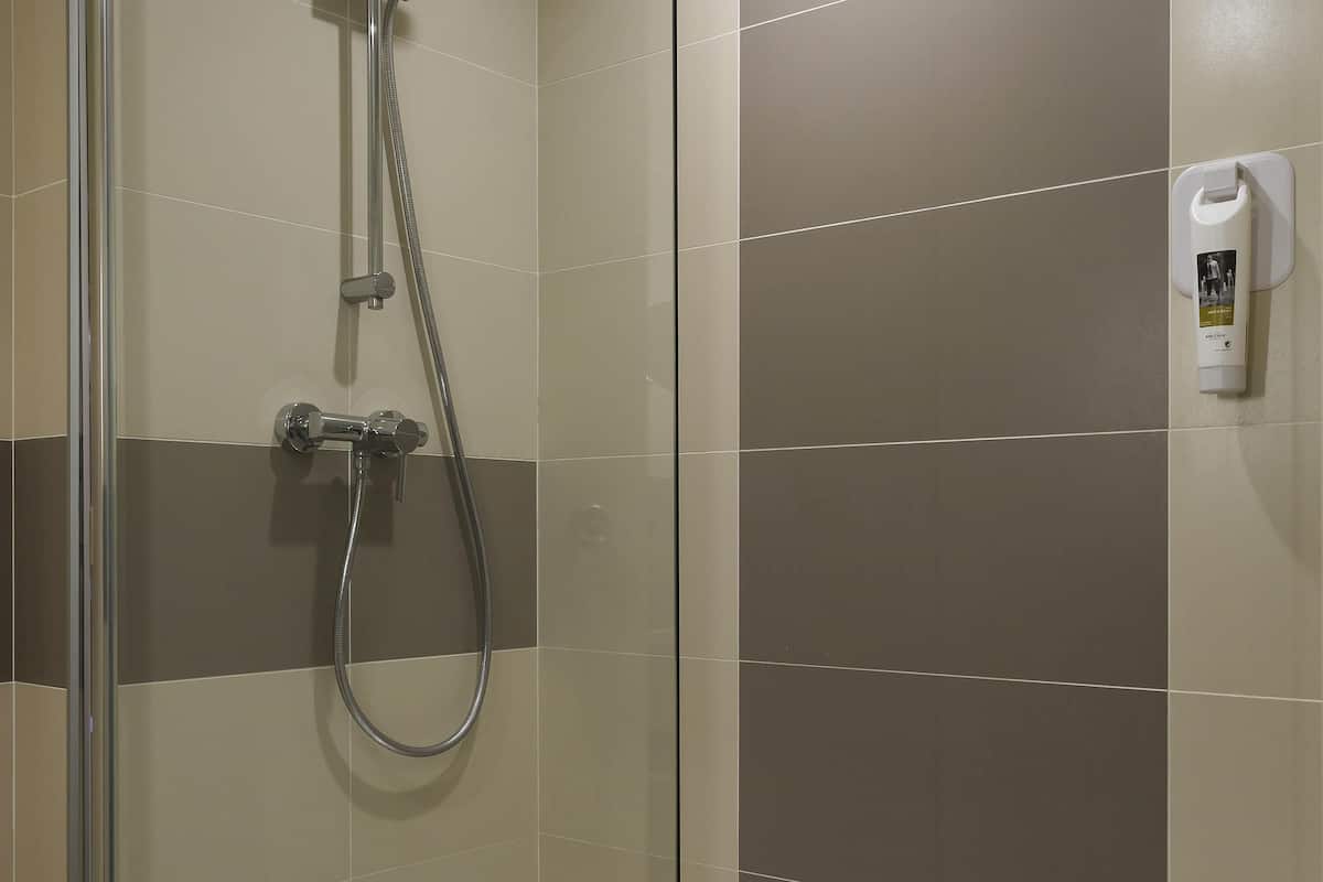 A shower with a handheld showerhead and a wall-mounted control panel.