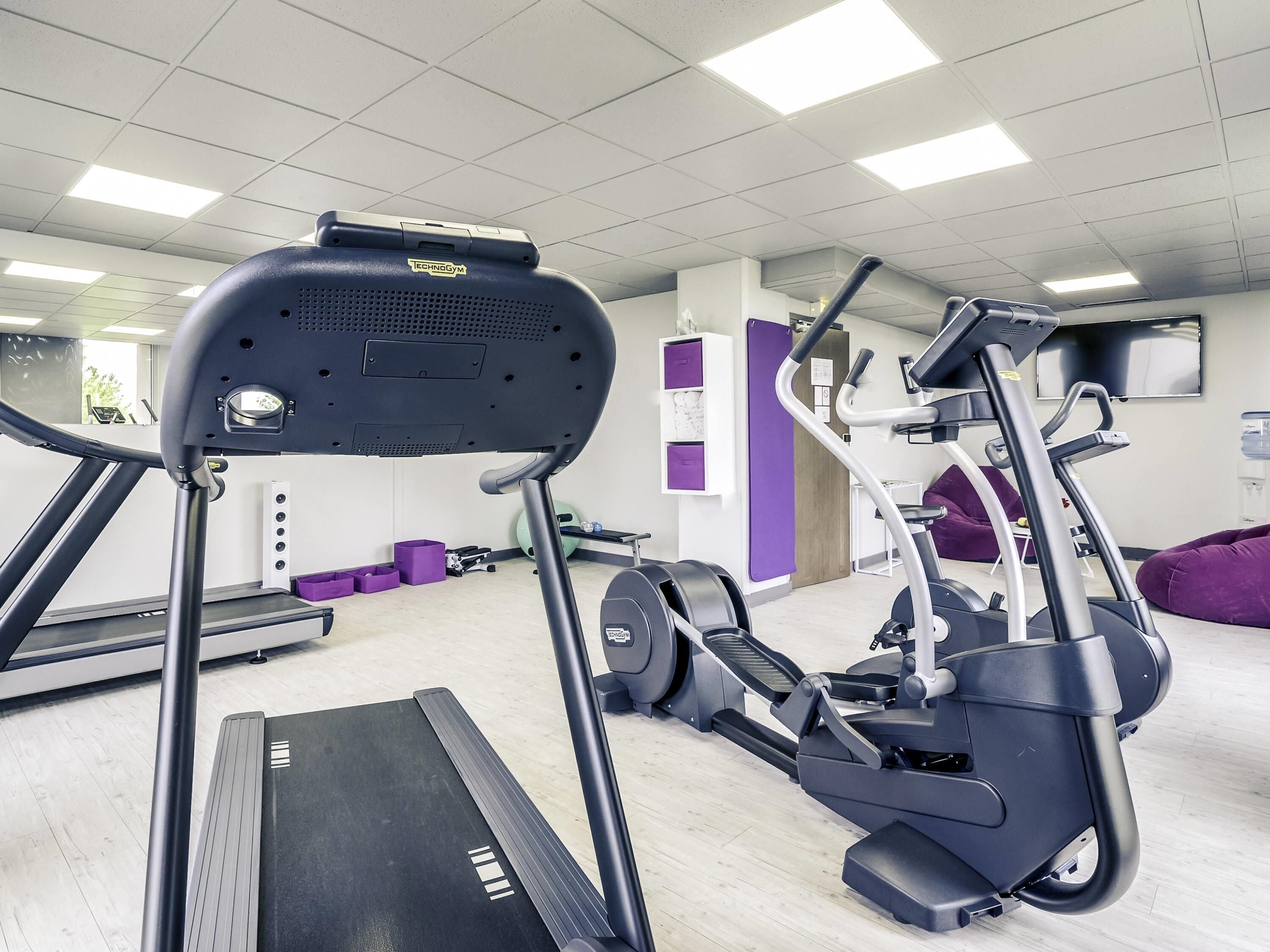A gym with treadmills, elliptical machines, and weight equipment.
