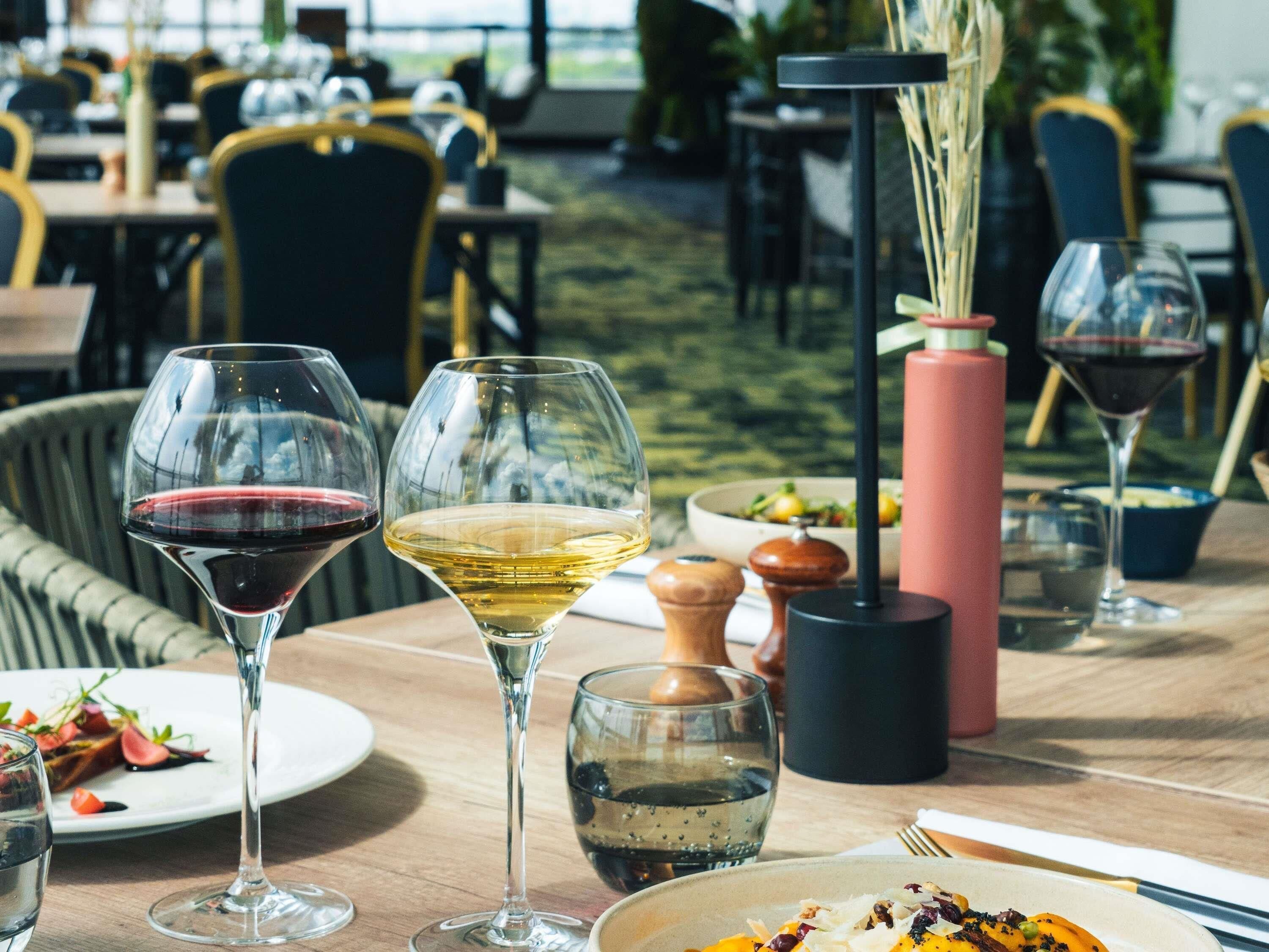 A dining area with tables, chairs, and wine glasses.