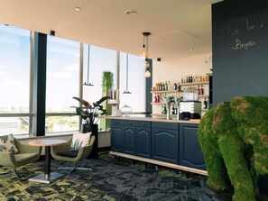 Een moderne bar met een toog, zitplaatsen en een groot raam met uitzicht op de stad.