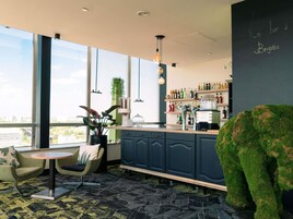 A modern bar area with a bar counter, seating, and a large window offering a city view.