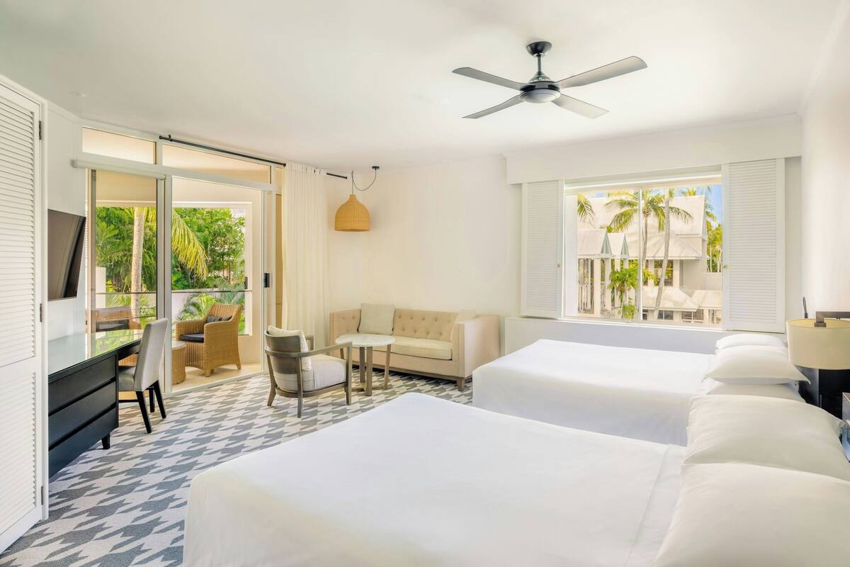 Habitación de hotel con dos camas, un sofá, un escritorio y un televisor.