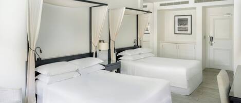 Ett hotellrum med två separata sängar, en takfläkt, ett skrivbord och en stol.