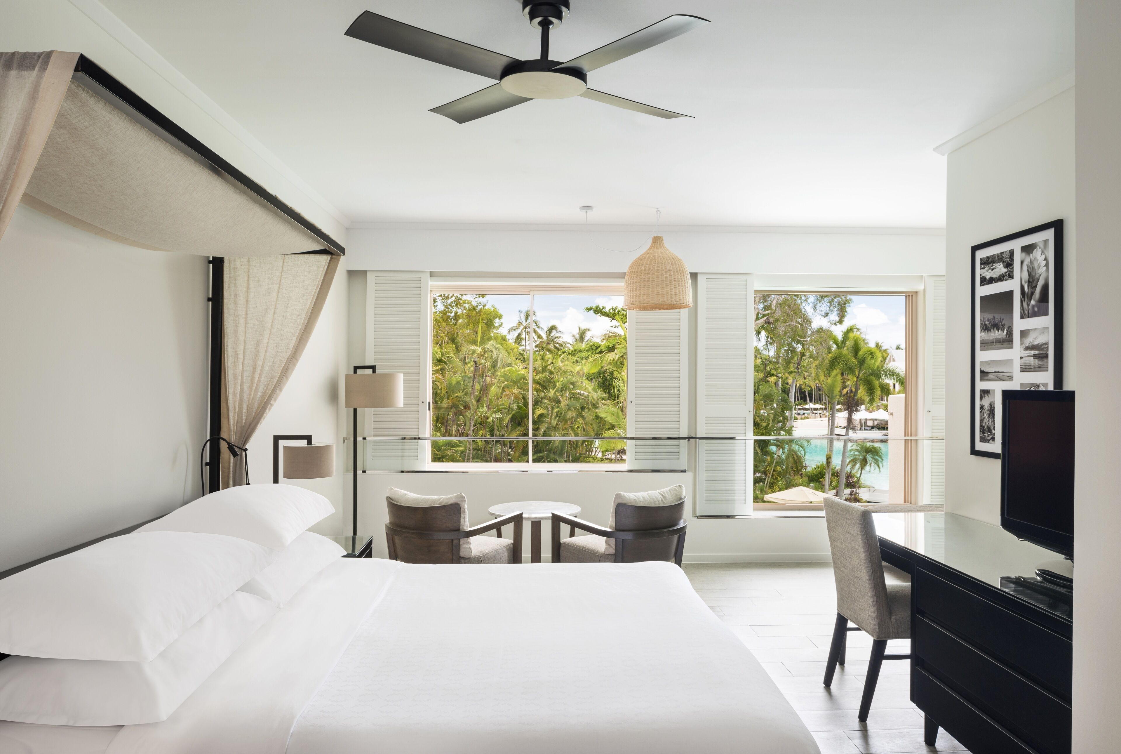 Une chambre d’hôtel moderne dotée d’un grand lit, d’un bureau et d’un balcon offrant une vue sur l’océan.