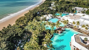An aerial view of a resort with a beach, a turquoise pool, and lush greenery. - Sheraton Grand Mirage Resort, Port Douglas (Port Douglas)