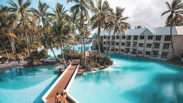A resort with a large swimming pool surrounded by palm trees and a hotel building. - Sheraton Grand Mirage Resort, Port Douglas (Port Douglas)