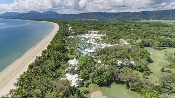 Eine Luftaufnahme eines Resorts mit Strand, üppiger Vegetation und einem Golfplatz.