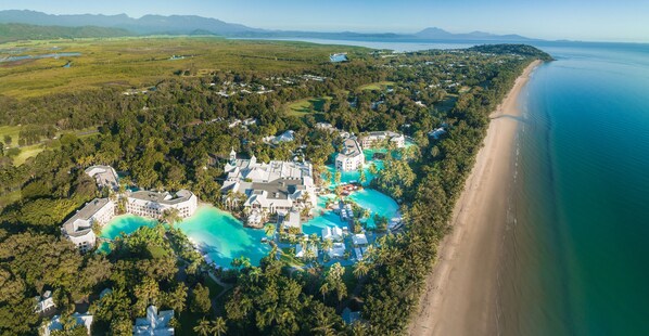 An aerial view of a resort with multiple swimming pools, a beachfront, and lush greenery. - Sheraton Grand Mirage Resort, Port Douglas (Port Douglas)