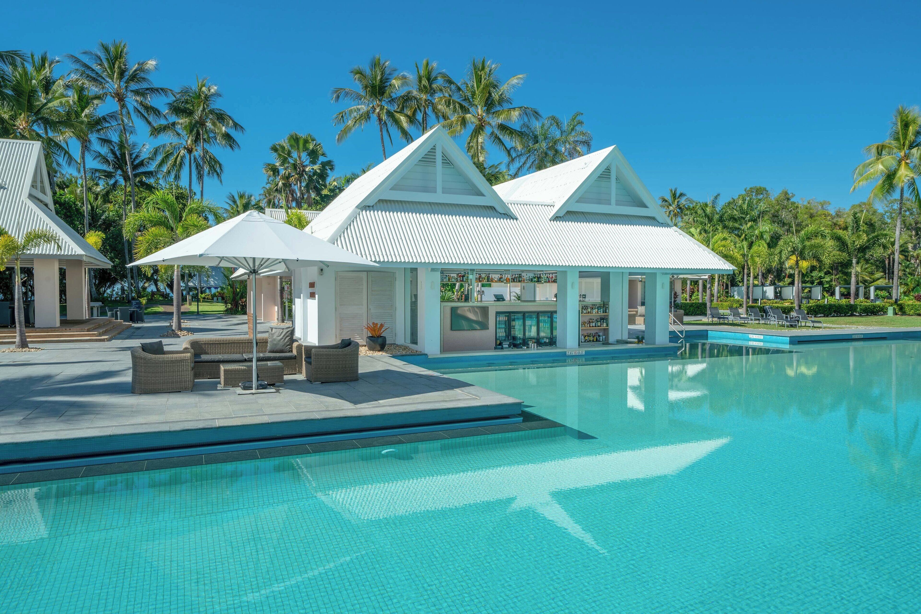 Een resort met zwembad, een loungegedeelte en strandparasols.