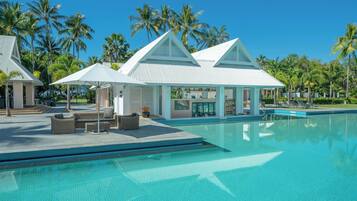 Een resort met zwembad, een loungegedeelte en strandparasols.