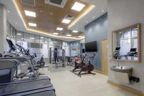 A gym with cardio machines, weight equipment, and a large mirror.
