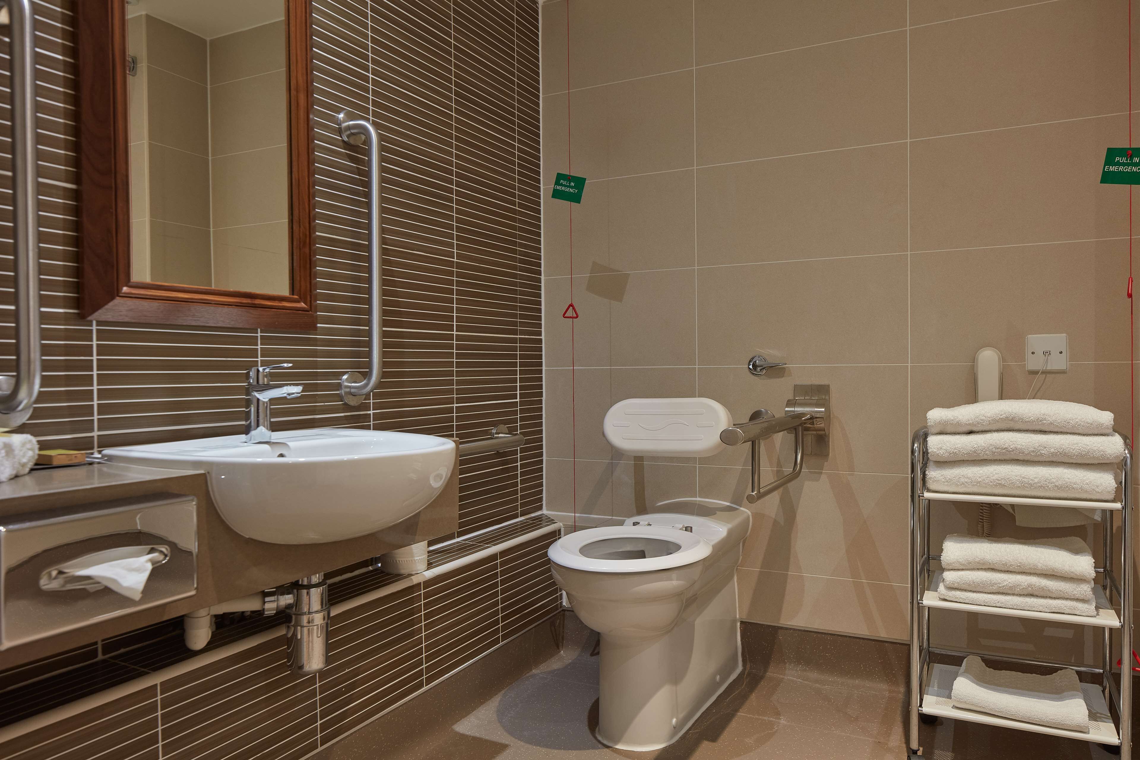 A modern bathroom with a sink, mirror, toilet, and towel rack.
