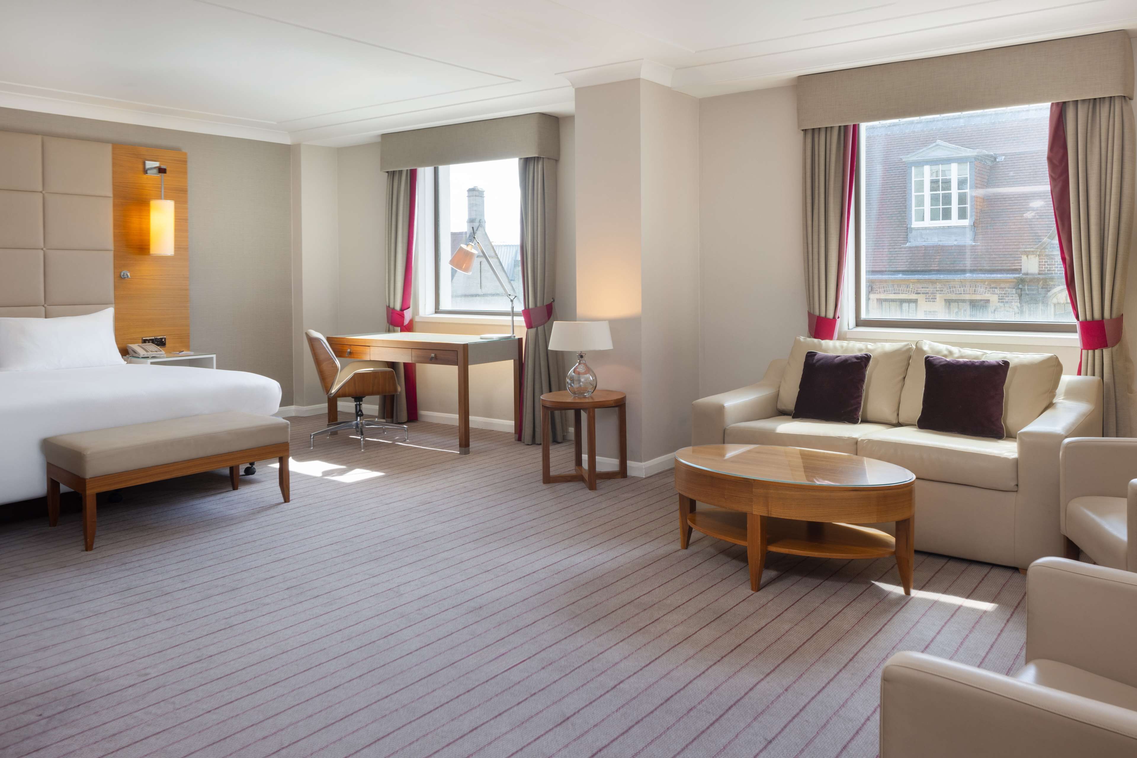 A hotel room with a bed, a desk, a sofa, and a coffee table.