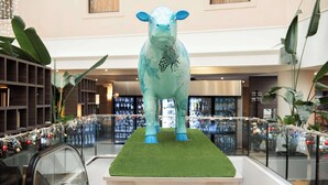 Una gran estatua decorativa de vaca sobre una plataforma en un centro comercial.