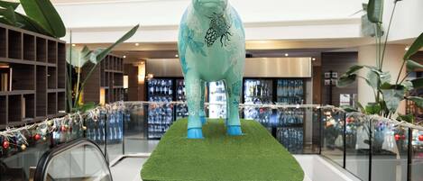 A large decorative cow statue on a platform in a shopping mall.