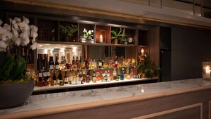 Una zona de bar con estantes llenos de botellas de licores, una encimera de mármol y plantas decorativas.