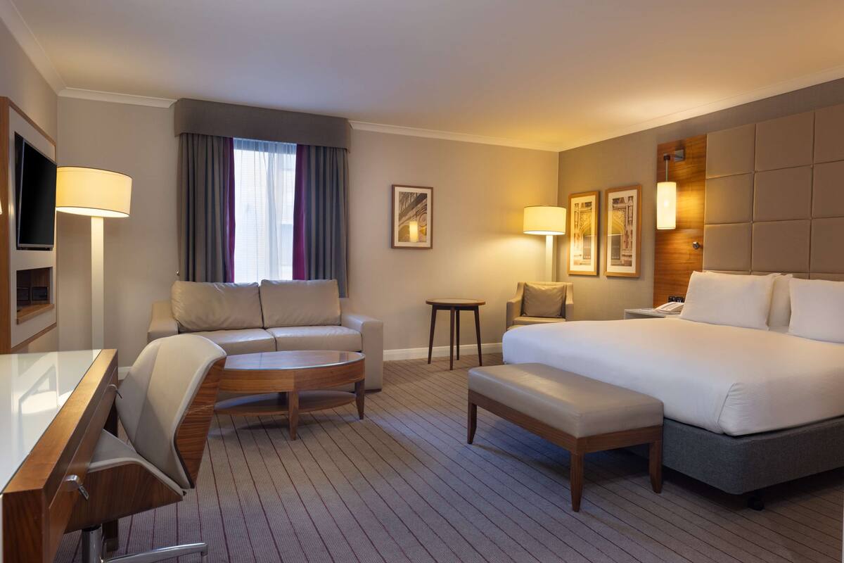 Una habitación de hotel con cama, sofá, escritorio y televisión.