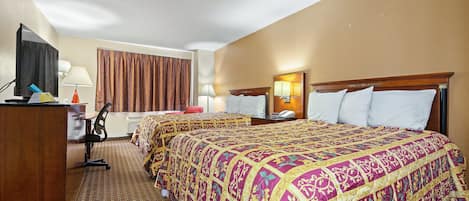 Een hotelkamer met een groot bed, een bureau met computer, een televisie en een raam met gordijnen.