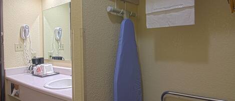 A bathroom with a sink, mirror, hairdryer, and towel rack.