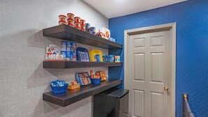 Una cocina con estantes de madera oscura que contienen diversos alimentos y una puerta blanca.