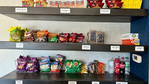 Estantes repletos de aperitivos y bebidas, como papas fritas, palomitas de maíz, galletas, dulces y refrescos.