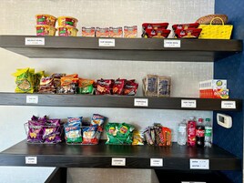 Estantes repletos de aperitivos y bebidas, como papas fritas, palomitas de maíz, galletas, dulces y refrescos.