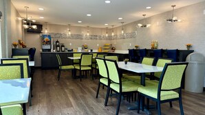 Un restaurante moderno con una zona de bar central, diversas opciones de asientos y una variedad de servicios, incluyendo una máquina de café y elementos decorativos.