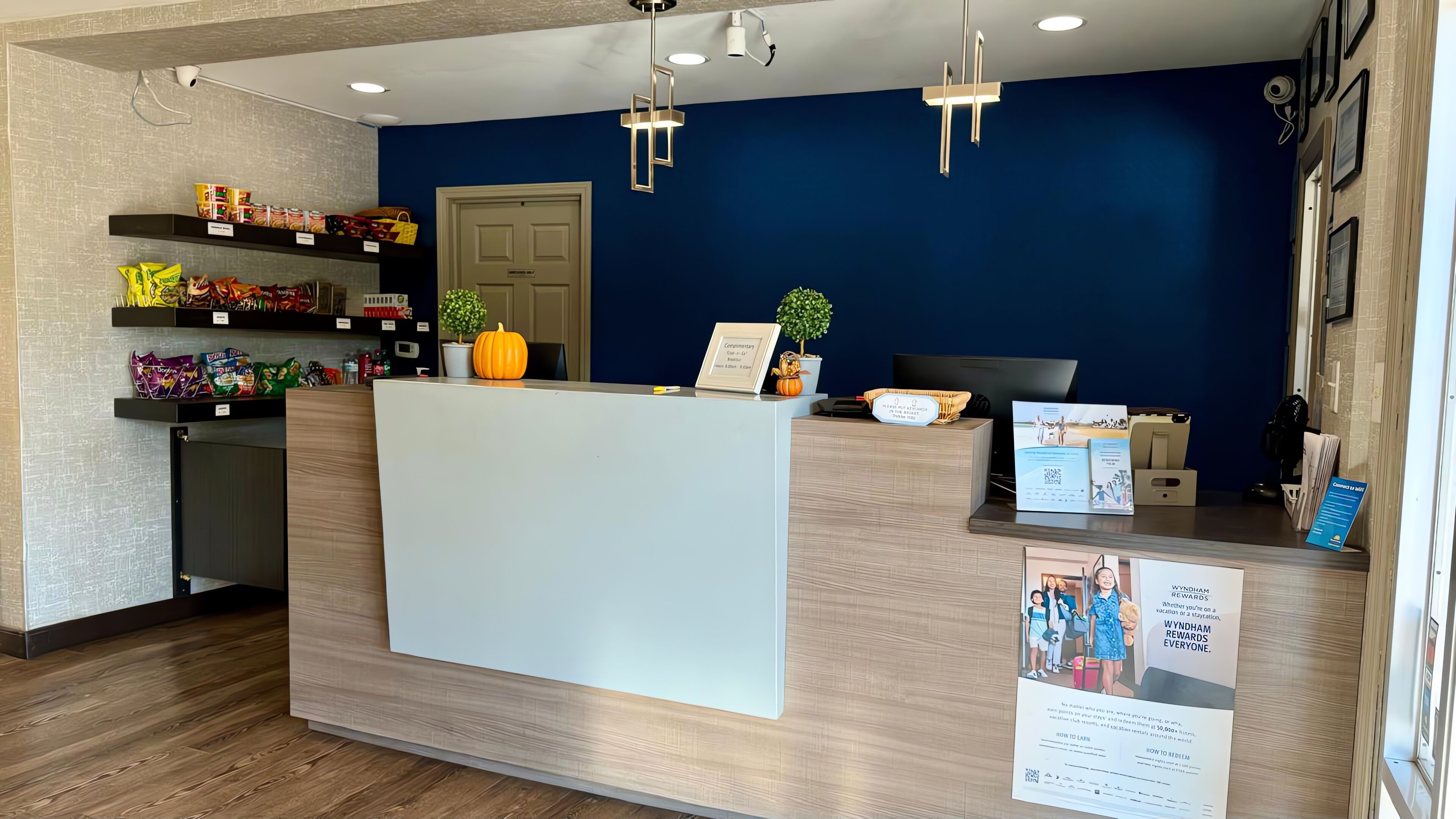 Un comptoir d’accueil avec un mur bleu, des étagères remplies d’en-cas, une plante en pot et un panneau indiquant les récompenses offertes.