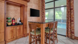 Una cocina con armarios de madera, un televisor de pantalla plana y un comedor con sillas.