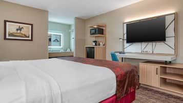 A hotel room with a bed, a TV, a desk, a microwave, and a cabinet.