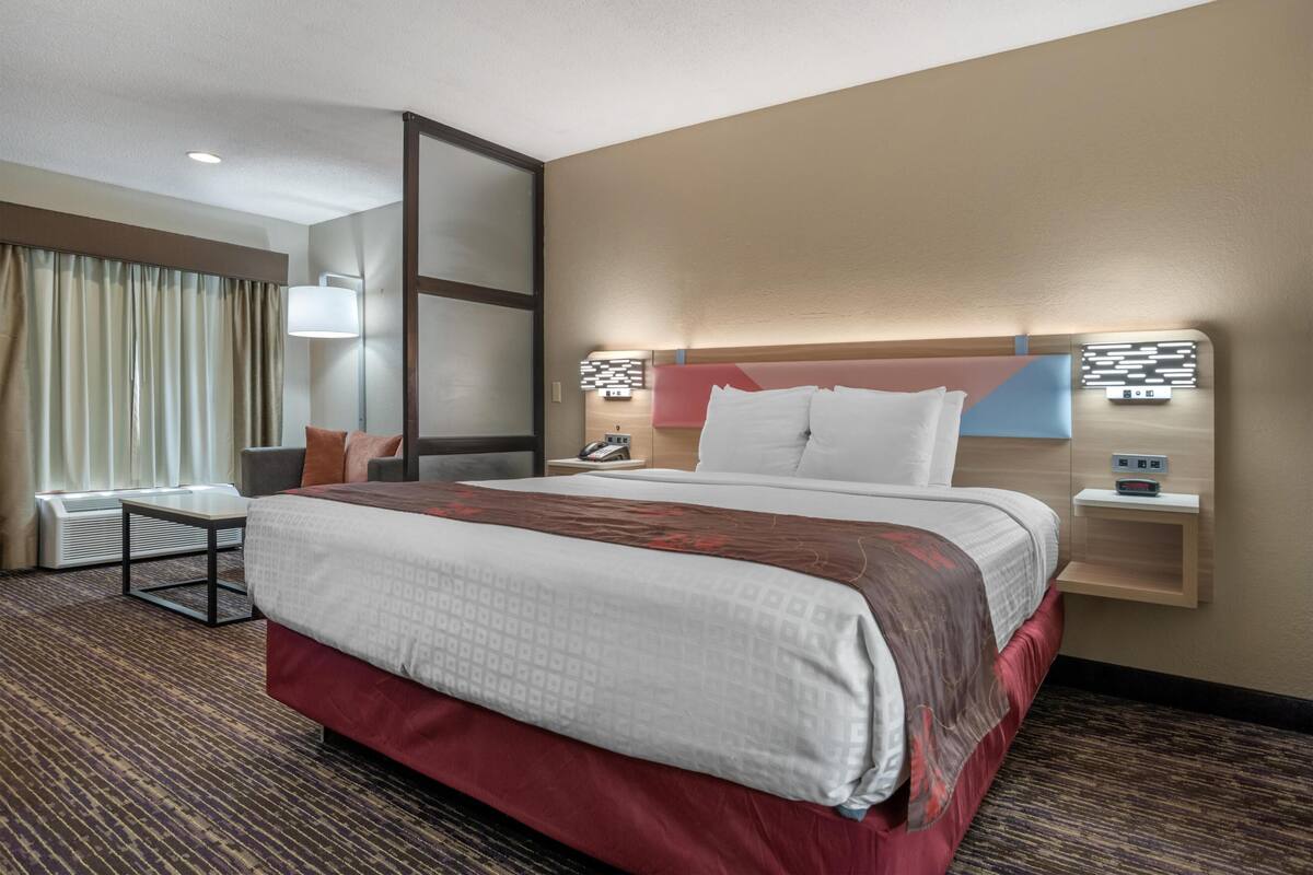 Een hotelkamer met een groot bed, nachtkastjes, een bureau en een stoel.