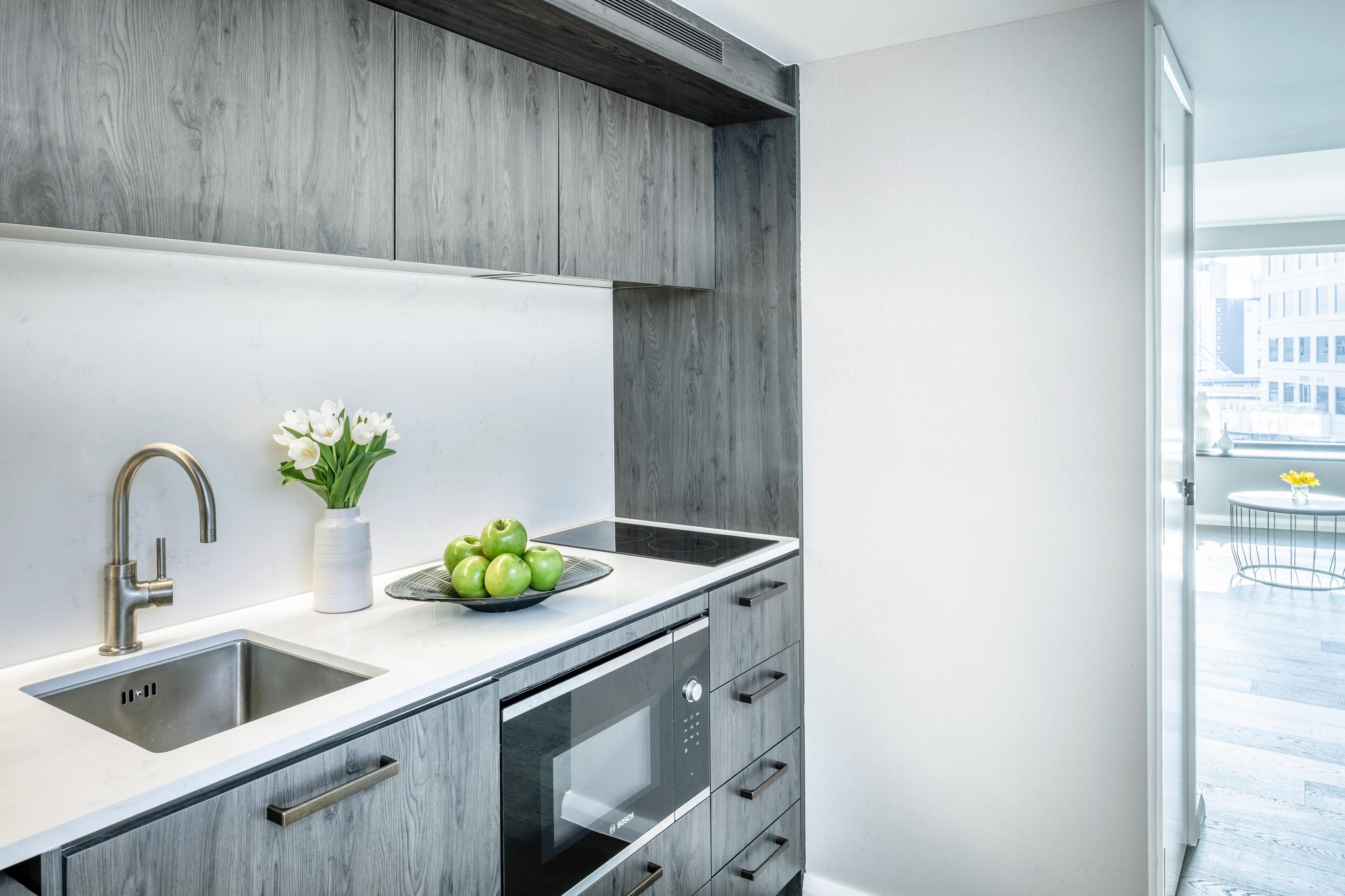 A modern kitchen with a built-in sink, a microwave, and a stainless steel oven.