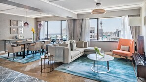 A modern hotel room with a dining area, a sofa, a coffee table, and a view of a cityscape. - Cordis, Auckland by Langham Hospitality Group (Auckland)