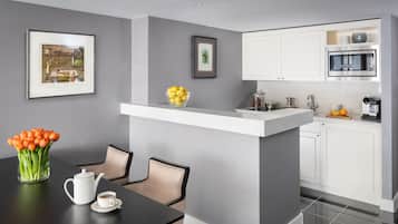 Cocina moderna con armarios blancos, microondas de acero inoxidable y una pequeña isla con un cuenco de limones.