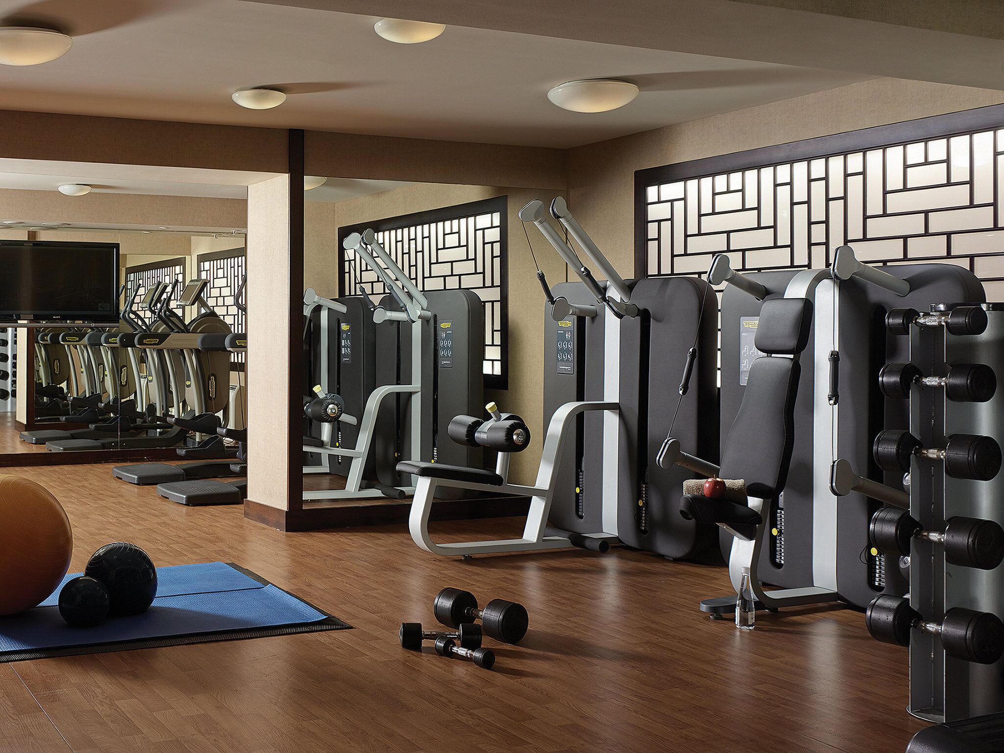 Uma academia com equipamentos de exercício, um espelho e um tapete azul.